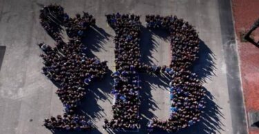 800 voluntarios crean un mosaico humano con el logo de la Copa América de Vela en Barcelona